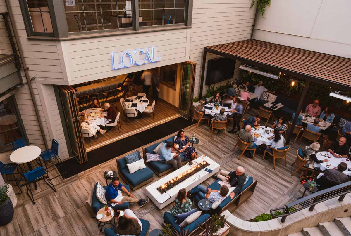 Guests dining on the lively patio beside the open bar at LOCAL Montecito